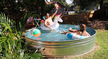 Load image into Gallery viewer, People playing in a homemade metal stock tank pool in a backyard